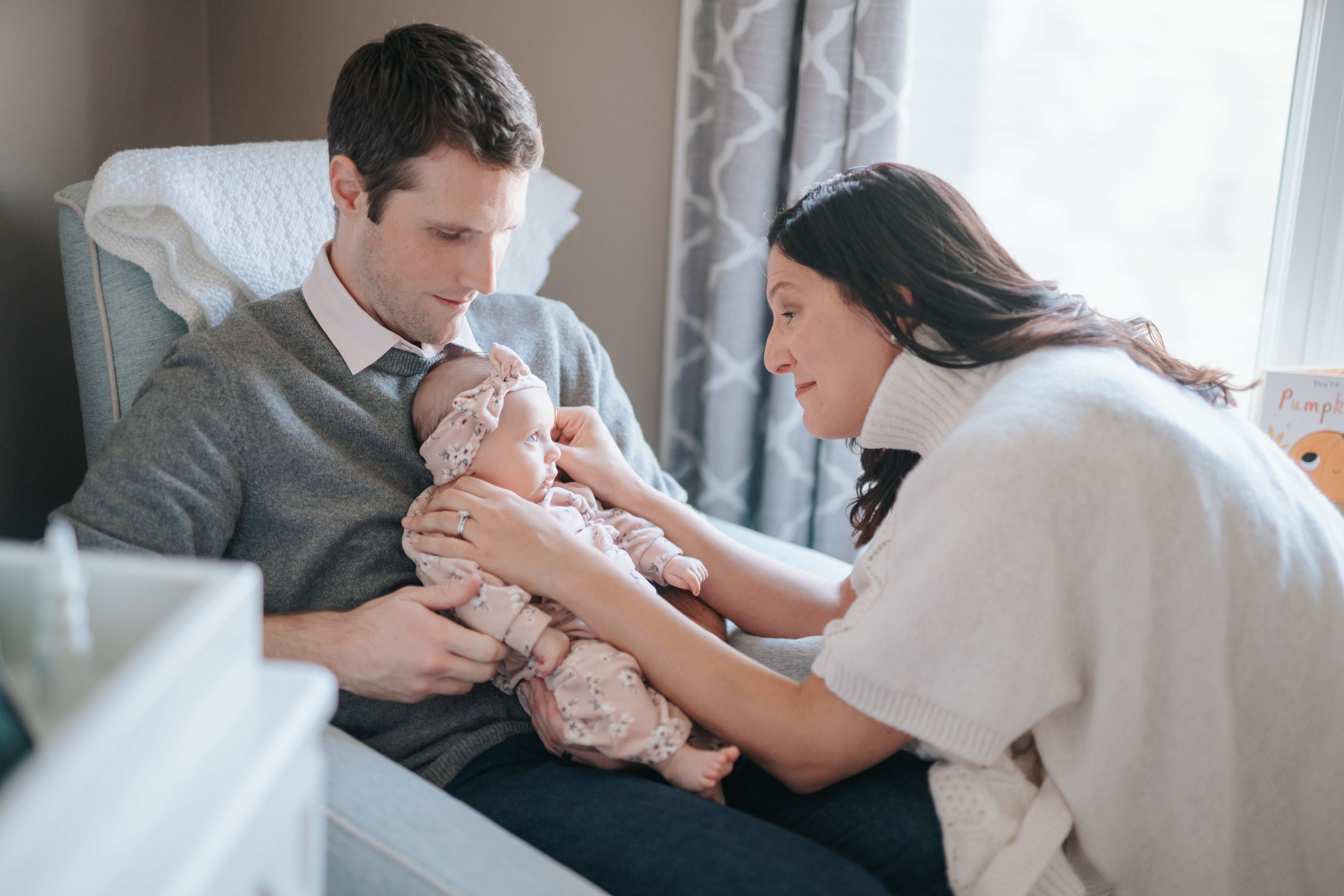 Parents looking lovingly at their newborn baby in a cozy nursery setting.