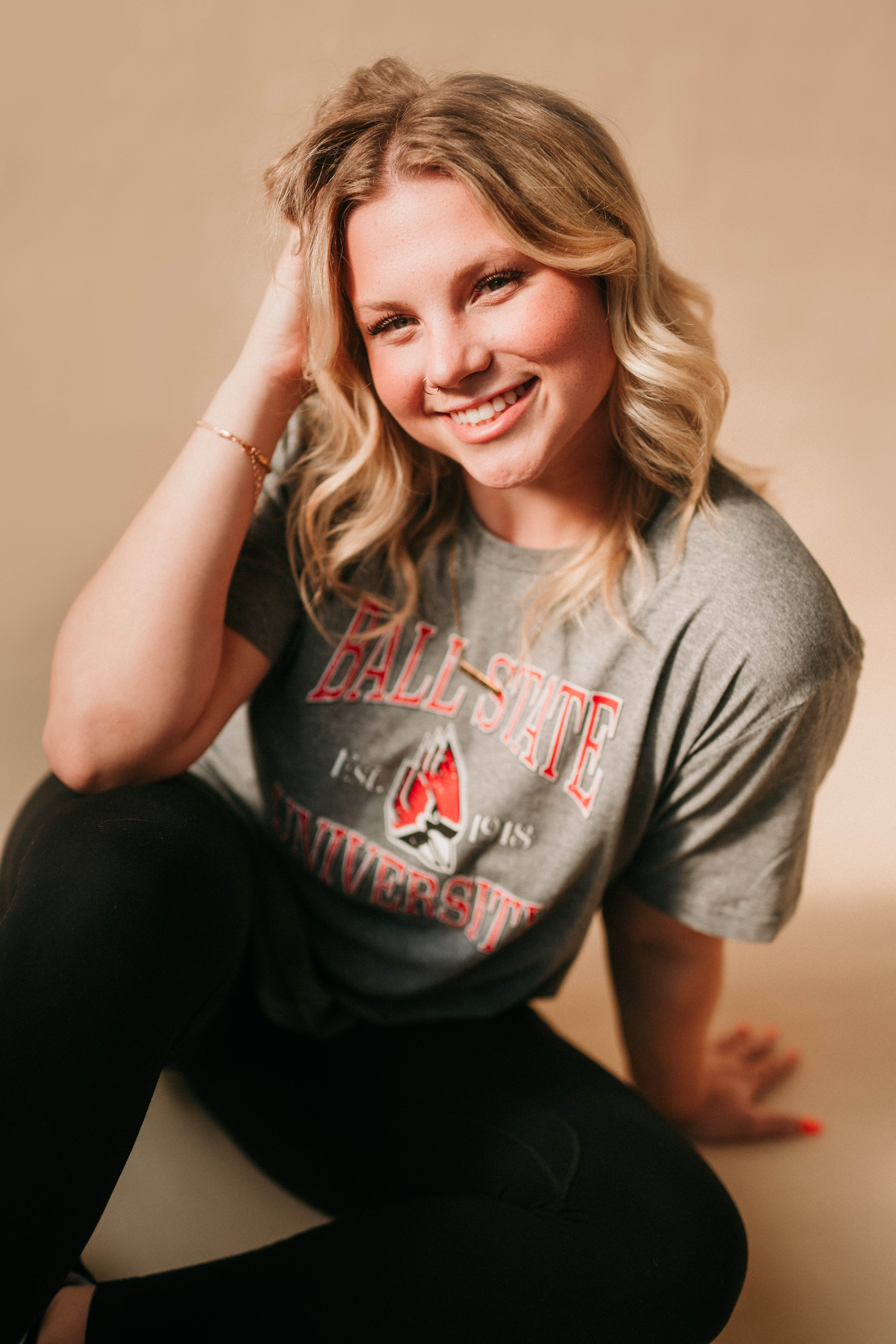 Smiling blonde senior wearing a Ball State University t-shirt in a studio.