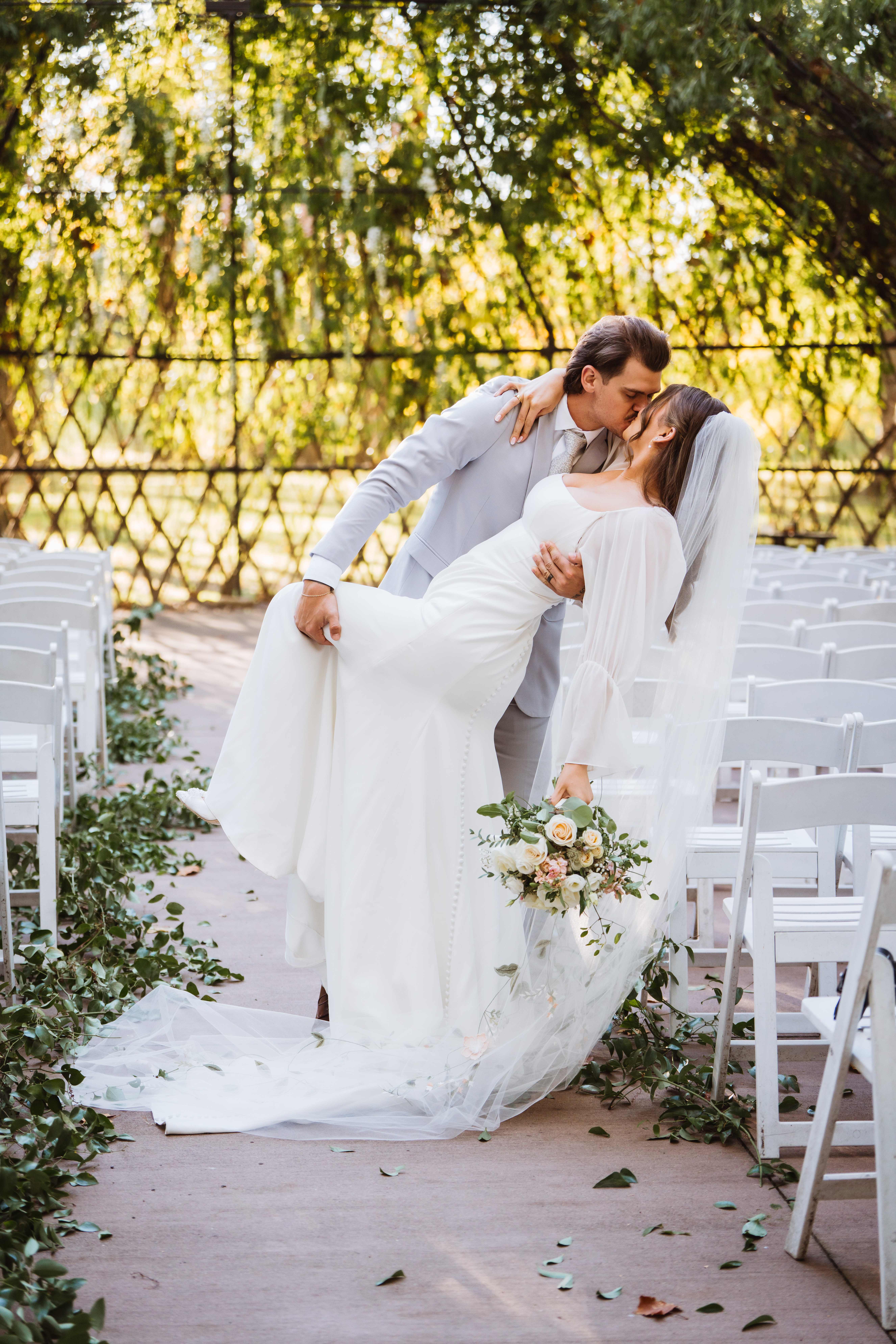 Groom dipping and kissing the bride at their outdoor wedding ceremony.
